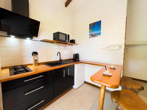 uma pequena cozinha com um lavatório e uma mesa em Bungalow le Balisier em Pointe-Noire