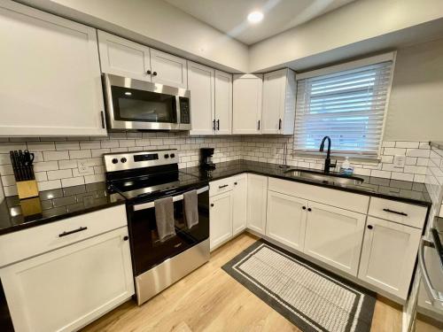 a kitchen with white cabinets and a stove top oven at Cathedral 7-New & Modern near UNMC in Omaha