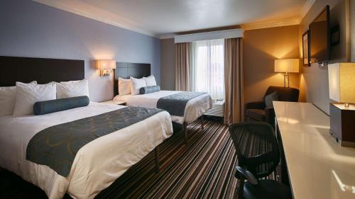 una habitación de hotel con 2 camas y una silla en Best Western Plus Diamond Valley Inn, en Hemet