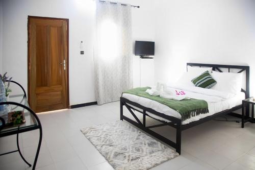 ein Schlafzimmer mit einem Bett mit einer grünen Decke in der Unterkunft Hôtel Camille in Nguékokh