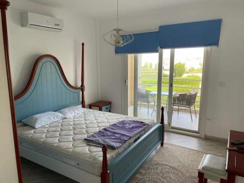 a bedroom with a bed with a blue headboard and a balcony at Duplex with Garden in Amwaj Sidi Abdel-Rahman-Beach & Pool Passes Included! in El Alamein
