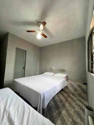 two beds in a bedroom with a ceiling fan at Pousada Sol in Goiânia