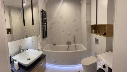 Baño blanco con bañera y lavamanos en Apartaments Airport Komputerowa Premium en Varsovia