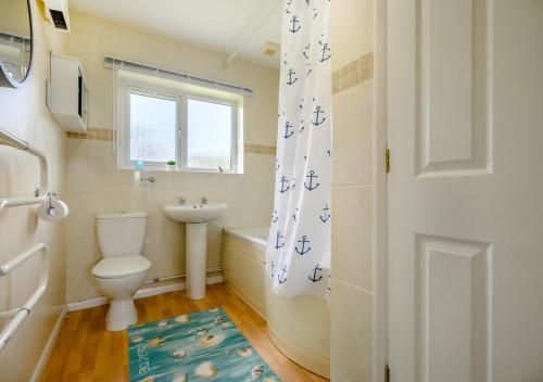 a bathroom with a toilet and a sink and a window at Trevelgue in Saint Merryn