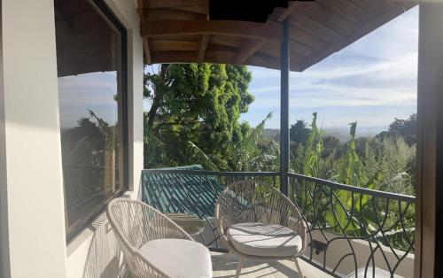 a balcony with two chairs and a view of trees at Villas Flakis, Vela in Monteverde Costa Rica