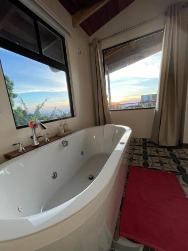 a large white bath tub in a bathroom with a window at Villas Flakis, Vela in Monteverde Costa Rica