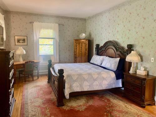 1 dormitorio con cama, mesa y ventana en Carriage House Inn, en Fredericton