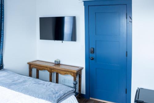 a bedroom with a blue door and a table at Van Wormer Room 201, Hyland Hotel in Palmer