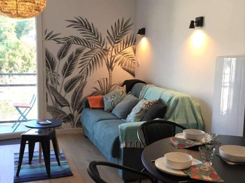 un salon avec un canapé bleu et une plante sur le mur dans l'établissement Appartement rénové avec balcon, parking et accès direct à la plage de Trestraou - Perros-Guirec - FR-1-368-260, à Perros-Guirec