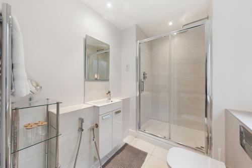 y baño blanco con ducha y aseo. en Modern 3BR Flat quick links to LDN & Heathrow, en Shepperton