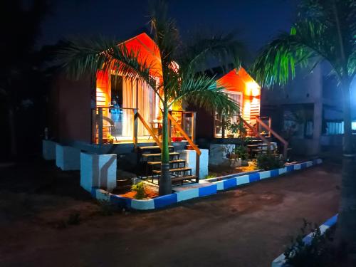 a house with a palm tree in the night at Chan Beach Resort & Hotel in Bahūr