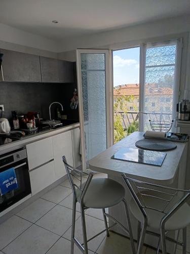 une cuisine avec une table et des chaises et une fenêtre dans l'établissement 2 pieces proche aéroport, à Nice