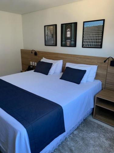 una camera da letto con un grande letto bianco con cuscini blu di Apartamento Hotel Itaipava Petropolis a Petrópolis