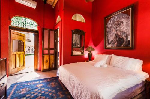 a bedroom with red walls with a bed and a doorway at Garlands Del Rio Riverside Boutique Hotel in Puerto Vallarta