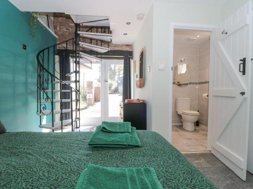 - une chambre avec un lit vert et une salle de bains dans l'établissement The Boar, à Blakeney