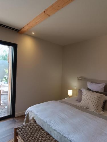 a bedroom with a bed and a large window at Hôtel Les Suites Du Maquis in Bonifacio