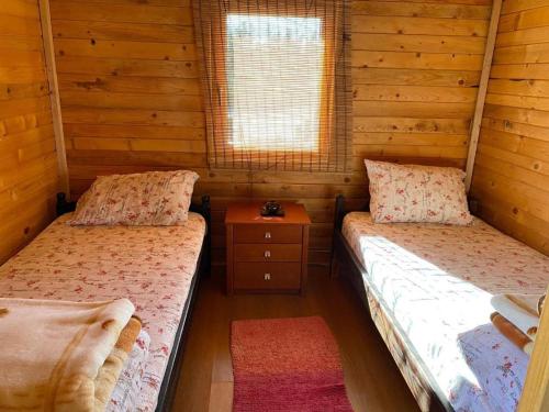 two beds in a room with wooden walls at Prenoćište Stupovi in Novi Pazar