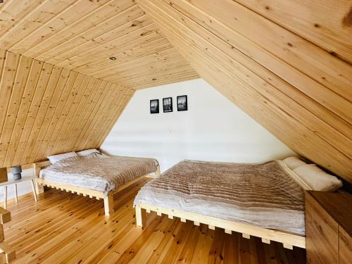 two beds in a room with wooden ceilings at Ostoja Drawno in Drawno