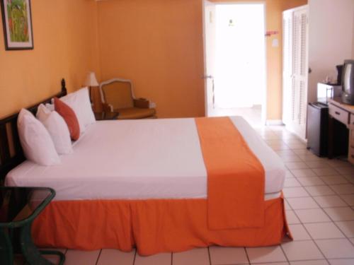 a bedroom with a large bed with an orange and white blanket at Pineapple Court Hotel in Ocho Rios