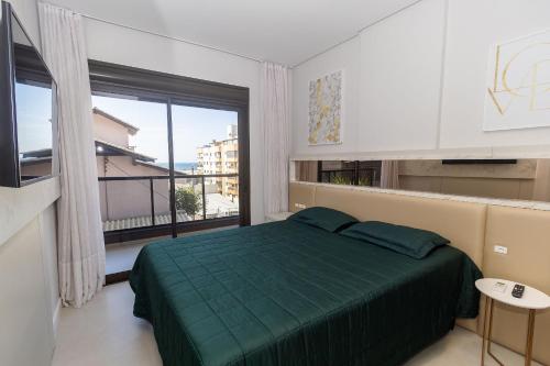 a bedroom with a green bed and a large window at Recanto dos Girassóis 206 - Excelente apartamento 2 quartos em prédio com piscina - à 200m do mar - (Consultar serviços de roupa de cama e banho) in Bombas