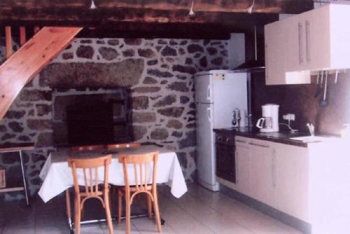 a kitchen with a table and chairs and a stone wall at Gîte de France Le fournil 3 épis - Gîte de France 2 personnes 564 in Égletons