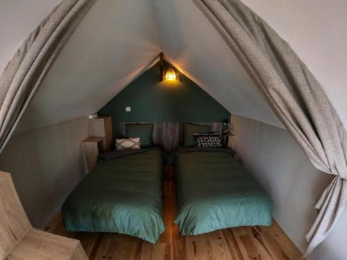 a bedroom with two green beds in a attic at Gîte de France L'écrin de lacoste 3 épis - Gîte de France 4 personnes 511 in Chasteaux