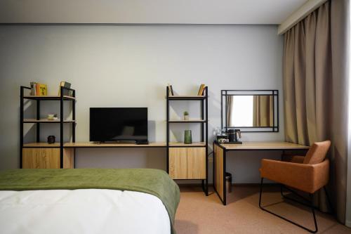 Dormitorio con cama, escritorio y TV en Felinger Collection Hotel & SPA, en Ereván