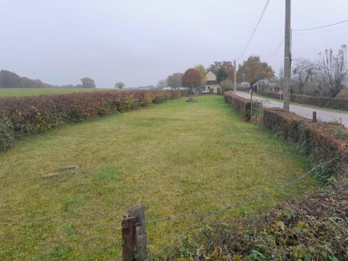 einen Zaun auf einem Feld mit einem Grasfeld in der Unterkunft Les Granges in Corbigny