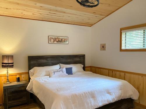 1 dormitorio con cama blanca y techo de madera en Casa on the Rocks, en Forest Lakes Estates
