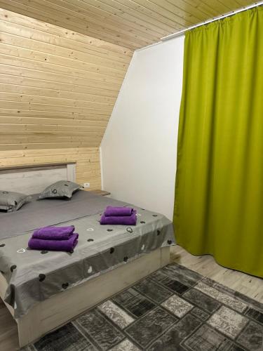 une chambre avec un lit avec des oreillers violets et un rideau vert dans l'établissement Casa de lemn 1,Tip A, à Corbu