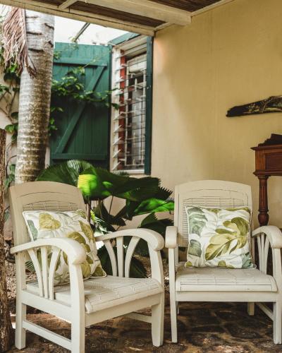 two white chairs and a bench on a porch at Harmonie in Rivière Noire
