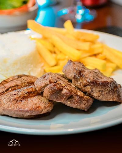 a plate of food with meat and french fries at Taj Hotel in Três Lagoas