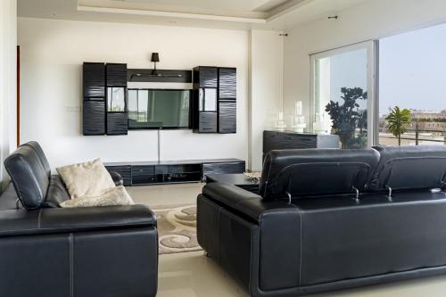 un soggiorno con mobili in pelle nera e una grande finestra di L'appartement Alpha Dakar a Dakar