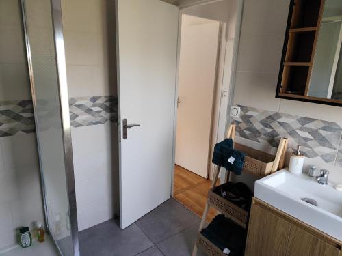 ein Bad mit einem Waschbecken, einem WC und einer Tür in der Unterkunft Appartement 6 personnes au calme à 25minutes de disney in Giremoutiers