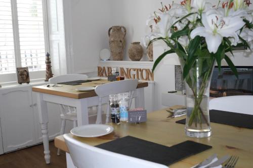 a dining room with a table with a vase of flowers at The Barrington Guesthouse Hotel in Scarborough