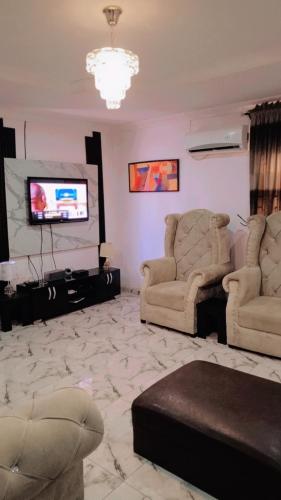 a living room with two chairs and a flat screen tv at J Lounge in Ikorodu