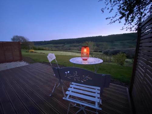 a table and chairs on a deck with a candle at Luxury Glamping In North Yorkshire National Park & Coastal Area in Scarborough