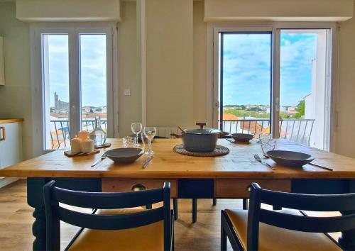 d'une table en bois avec des chaises et des bols. dans l'établissement Appartement lumineux proche plage et marché, centre-ville accessible à pied parking gratuit inclus I SWEET HOMES LOCATION, à Royan