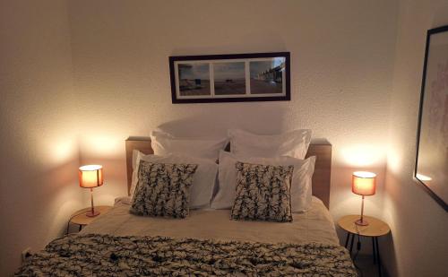 una camera da letto con un letto con cuscini e due lampade di Face à la mer Corinne a Mers-les-Bains
