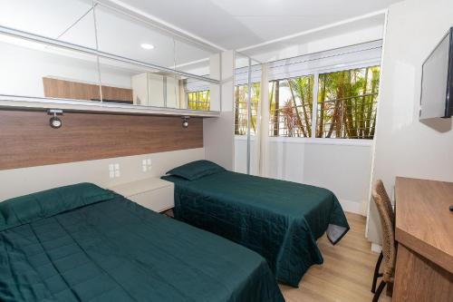 a bedroom with two beds and a table and window at Varandas do Atlântico 01B - Excelente apartamento em condomínio de luxo a beira mar - Piscina climatizada - Academia - (Consultar serviços de roupas de cama e banho) in Bombas