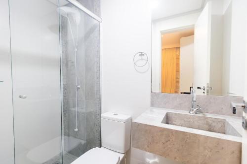a bathroom with a shower and a toilet and a sink at Varandas do Atlântico 01B - Excelente apartamento em condomínio de luxo a beira mar - Piscina climatizada - Academia - (Consultar serviços de roupas de cama e banho) in Bombas