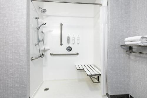a white bathroom with a shower and a bench at Hampton Inn Kingsville in Kingsville