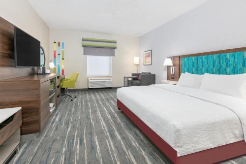 a hotel room with a bed and a flat screen tv at Hampton Inn Kingsville in Kingsville