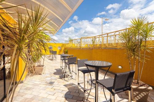 a patio with tables and chairs on a balcony at Hotel Dan Inn Ribeirão Preto By Nacional Inn in Ribeirão Preto