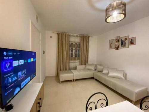 a living room with a couch and a flat screen tv at Charme Bleue-Appartement Magique in Monastir