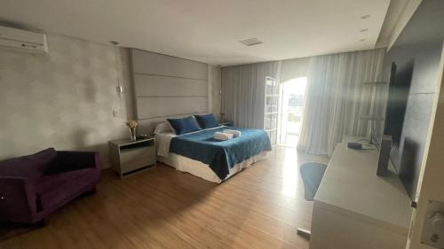 1 dormitorio con 1 cama, 1 silla y TV en Mansão Casa Blanca em São Roque c/ 5 vagas garagem en São Roque