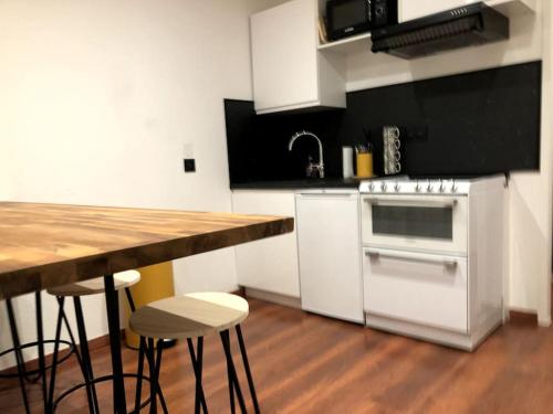 a kitchen with a white stove and a counter with stools at Gare - Elégant appartement pour pros ou touristes in Chambéry