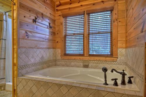 a bathroom with a large tub in a room with wooden walls at Crescent Moon on the River in Ellijay