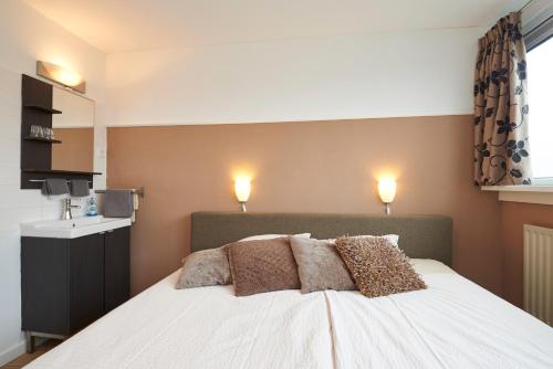 1 dormitorio con 1 cama blanca y 2 almohadas en B&B HutSpot en Ámsterdam