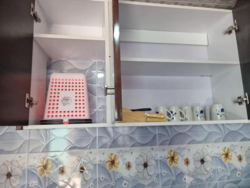 a kitchen cabinet with a red and white box in it at Finland in Migori